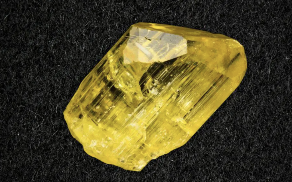 a yellow crystal on a black surface